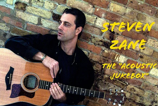 Steve holding guitar looking down by brick wall